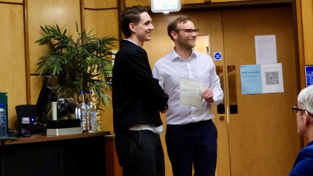 Two men shaking hands with certificate