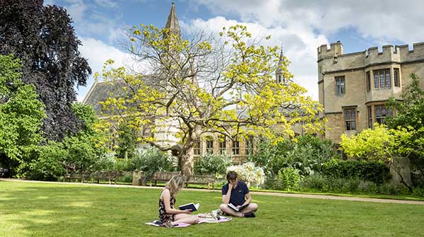 Two students reading on law in Garden Quad, view of Chapel and Old Library behind