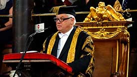 Chris Patten in academic dress standing at lectern